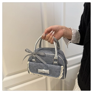 Close-up of bow detailing and lace trim on the grey denim Boston handbag