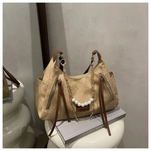 Détail du sac cabas kaki avec gland en cuir marron foncé et accents de perles dorées