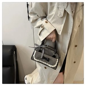 Detail of grey bow handbag featuring delicate white lace trim and checkered ribbon decoration