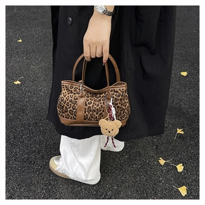 Detail of leopard print suede handbag with brown leather handle and cute plush bear charm