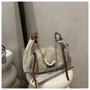 Détail d'un cabas en toile avec lanières en cuir marron et chaîne en perles