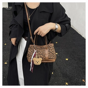 Detailed shot of leopard print canvas handbag with bear pendant and scarf on a model