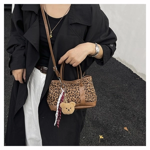 Close-up of leopard print mini handbag with brown leather strap and plush bear charm