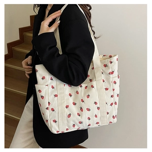 Détail du sac fourre-tout en velours crème avec imprimé fraise et poche latérale pratique