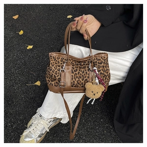Detail of leopard print mini tote bag with brown leather handles and plush bear charm