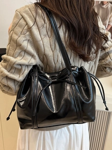 Glossy black PU leather tote bag with bow detail and drawstring on a model