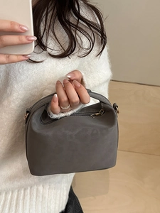 Minimalist grey semi-circular handbag with a wide handle and matte finish texture