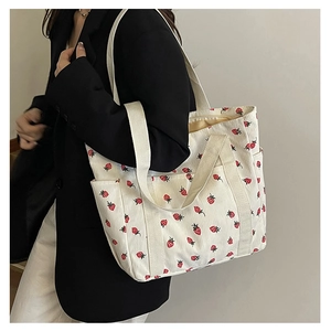 Vue détaillée du sac fourre-tout en velours côtelé crème avec motifs de fraises rouges