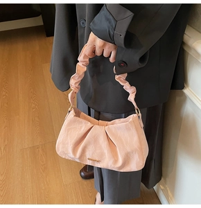 Dettaglio della borsa a pieghe rosa chiaro con texture morbida e logo dorato