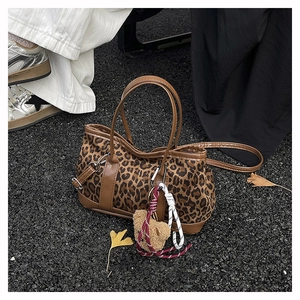 Detail of leopard print suede bucket bag with plush bear charm on autumn ginkgo leaves