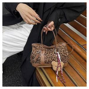 Detail of leopard print handbag with brown leather trim and cute plush bear charm