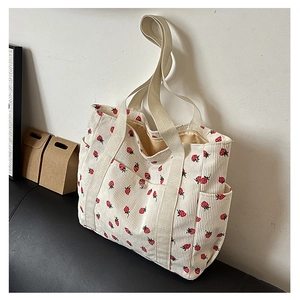 Détail du sac cabas en velours côtelé écru avec imprimé fraise et poches latérales