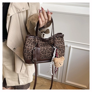 Detailed view of leopard print handbag featuring teddy bear charm and silver hardware
