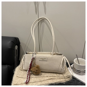Detail of cream baguette bag with side drawstring bow and plush bear charm accent