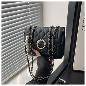 Detailed view of black quilted bag with gold pearl buckle and pearl chain strap