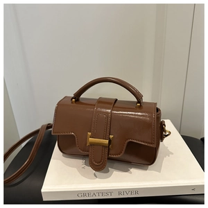 Détail d'un sac à main vintage en cuir marron avec boucle dorée et poignée élégante