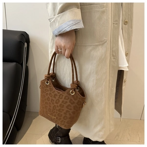 Detail of leopard print bucket bag featuring knotted handles and gold metal eyelets