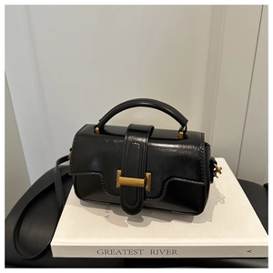 Détail du sac bandoulière en cuir noir avec fermoir doré et poignée supérieure élégante