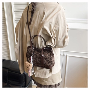 Detail of leopard print bucket bag with brown leather trim and cute bear plush charm