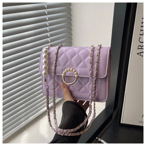 Detailed macro view of a lavender quilted pearl chain bag with round pearl metal buckle