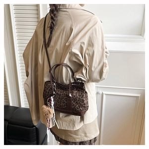 Detail of leopard print suede tote bag with plush bear charm and ribbon on model