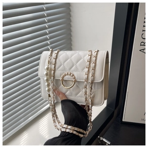 Detail of white quilted crossbody bag with golden chain and large pearl strap accents