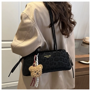Detail of leopard print shoulder bag with cute bear charm and fashion brand logo