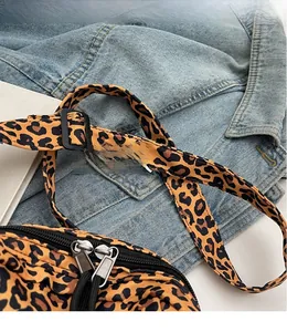 Detail of leopard print crossbody bag with adjustable shoulder strap and double zippers