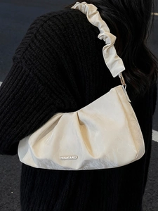 Borsa a spalla plissettata in raso bianco crema con logo metallico su sfondo maglione nero