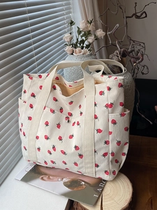 Sac cabas en velours côtelé avec imprimé fraises et poches latérales près d'une fenêtre