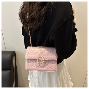 Detail of light pink quilted crossbody bag with pearl buckle and metal chain strap