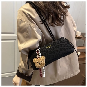 Detail of leopard print underarm bag with plush bear charm and brand label close-up
