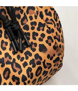 Close-up of leopard print canvas fabric and black drawstring detail on a small crossbody bag