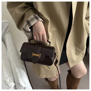 Sac à main classique en cuir marron foncé porté avec un trench-coat beige élégant