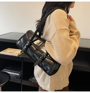 Detail of black glossy patent leather shoulder bag with decorative metal buckle straps