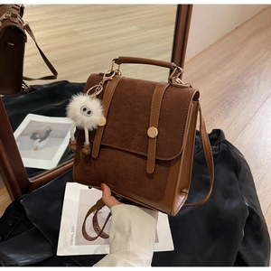 Detail of dark brown faux suede backpack with gold magnetic clasp and plush charm accessory