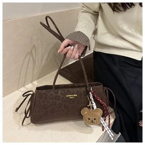 Detail of leopard print underarm bag with plush bear charm and woven cord accents