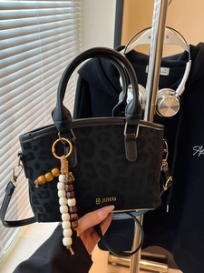 Women's black leopard suede handbag with gold buckle and beaded charm in a lifestyle view