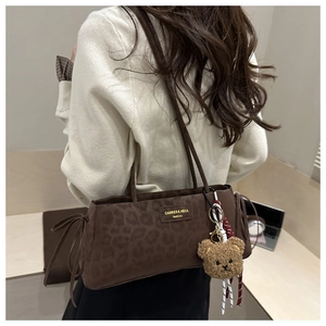 Detail of leopard print shoulder bag with gold logo and plush bear charm accessory