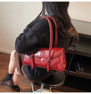 Detail of burgundy glossy baguette shoulder bag showing leather texture and buckles