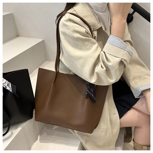 Close-up of a large brown textured leather tote bag with a decorative floral silk scarf