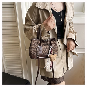 Close-up of vintage leopard print crossbody bag with plush bear charm detail