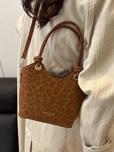 Brown leopard print suede bucket bag with gold circular handles and crossbody strap