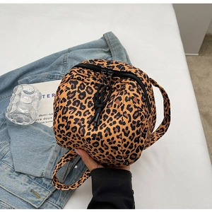 Detailed close-up of a round leopard print handbag with zipper on denim background