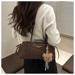 Close-up of leopard print baguette bag with soft velvet texture and plush bear charm