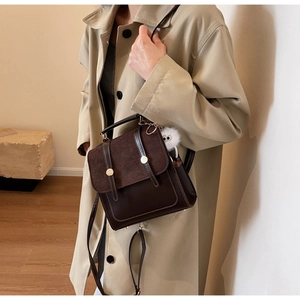 Close-up of vintage brown leather handbag with gold metal buckle and plush charm detail