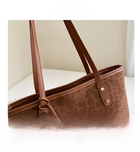 Close-up of leopard print tote bag featuring golden rivets and brown leather handles