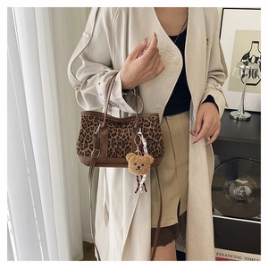 Detail of leopard print shell bag with brown leather trim and cute plush bear charm