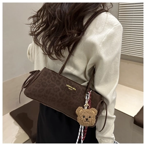 Detail of leopard print suede shoulder bag with drawstring tassels and plush bear charm
