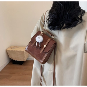 Close-up of retro brown PU leather shoulder bag with plush pendant and flap detail